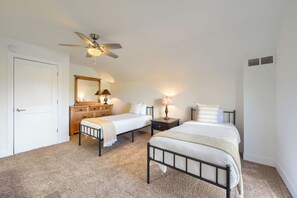 A bedroom with two single beds, a ceiling fan, a dresser, and a mirror.