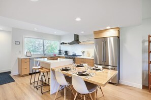 Una cocina moderna con una isla central, electrodomésticos de acero inoxidable y un comedor con sillas.