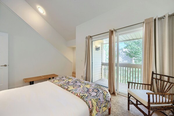 A bedroom with a bed, a chair, a bench, and a view of the outdoors.