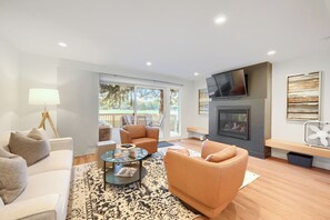 Una sala moderna con sofá, sillón, mesa de centro y chimenea.