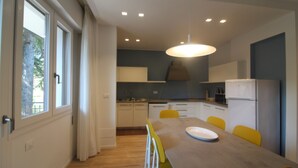 Een moderne keuken met een eettafel, stoelen en een koelkast.