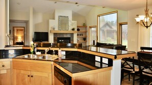 A modern kitchen with a central island, built-in appliances, and a large window providing natural light. - Cozy Home on the Idaho side of the Teton mountains- AC and a View! (Driggs)
