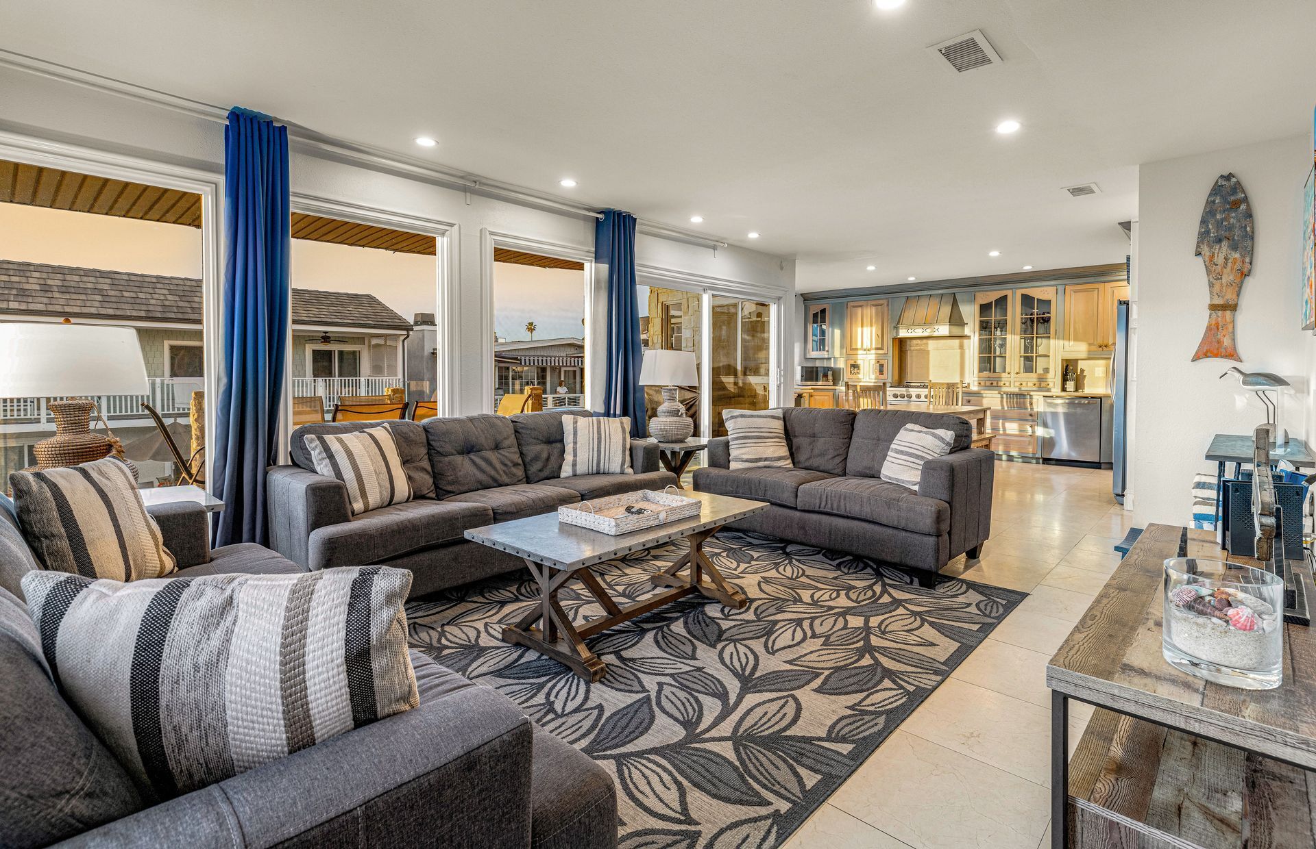 A spacious living room with a large gray sectional sofa, a coffee table, and a patterned rug.