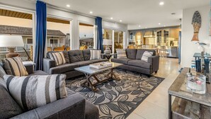 Ein geräumiges Wohnzimmer mit einem großen grauen Ecksofa, einem Couchtisch und einem gemusterten Teppich.