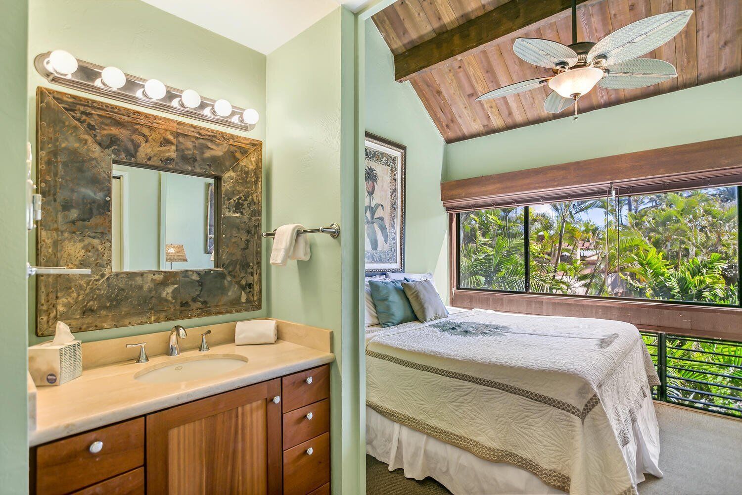 A bathroom with a large mirror, vanity, and a ceiling fan.