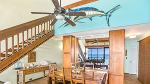 A spacious dining area with wooden furniture and a view of the ocean through large windows.