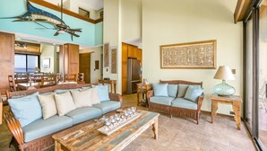 A spacious living area with a large sofa, a coffee table, and a dining area with chairs and a table.