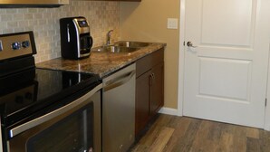 Une cuisine avec des meubles de rangement en bois, un four à micro-ondes, une cuisinière, un lave-vaisselle et un évier.