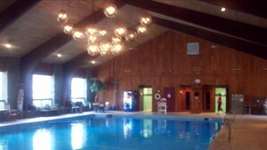 Une piscine intérieure avec un plafond et des murs en bois, une eau cristalline et un poste de surveillance pour le sauveteur.