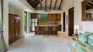 A spacious kitchen with a bar area, wooden cabinets, and a ceiling with exposed beams. - Idyllic Island Getaway, Private Beach Deck & Access (Providenciales)