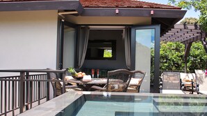 A modern outdoor pool area with a glass enclosure, wicker furniture, and a view of the surrounding landscape. - Idyllic Island Getaway, Private Beach Deck & Access (Providenciales)
