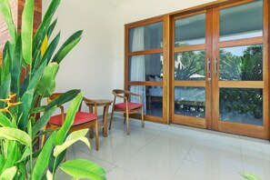 Ein Zimmer mit einer Schiebetür zum Balkon, einem kleinen Tisch mit zwei Stühlen und einem Blumentopf.