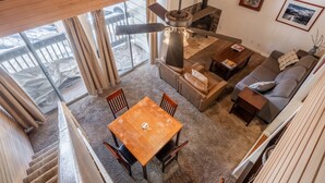 Ein geräumiges Wohnzimmer mit hohen Decken, einem Kamin, einem Essbereich und einem Sofa.