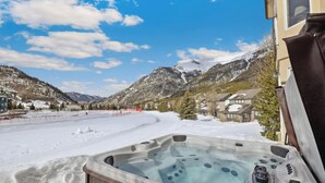Ein Whirlpool mit Blick auf die Berge, umgeben von Schnee und Häusern.