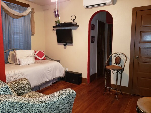 Een slaapkamer met een bed, een stoel, een televisie en een deur.