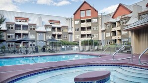 Un hotel con piscina, zona de estar al aire libre y un edificio de varios pisos con balcones.