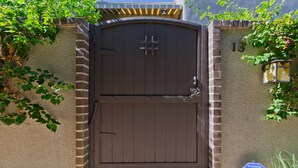 A brown metal gate with a keypad lock, a brick wall, and a house number 13. - Designer Townhouse in the heart of Palm Springs, Convention Center. CITY ID#3867 (Palm Springs)