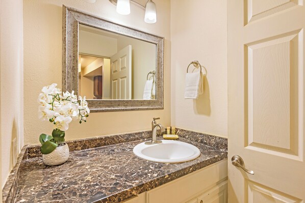Une salle de bain avec un lavabo en marbre, un miroir et une orchidée en pot.