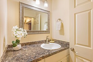 Une salle de bain avec un lavabo en marbre, un miroir et une orchidée en pot.