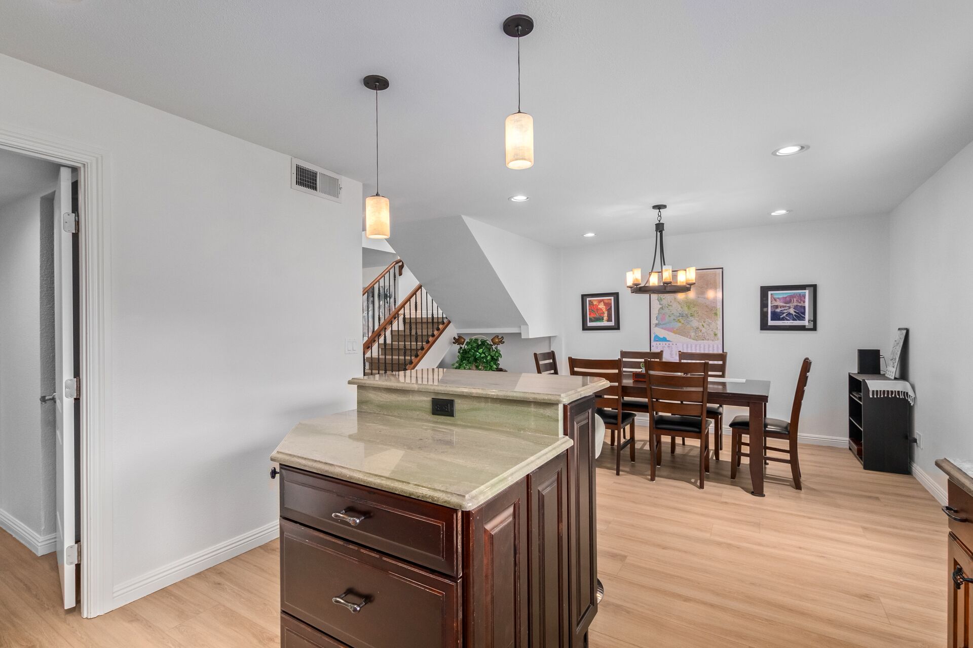 A modern kitchen with a central island, wooden cabinets, and pendant lighting.