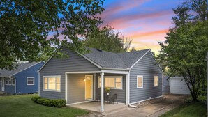 Ett bostadshus med en inglasad veranda, ett garage och en välskött gräsmatta.