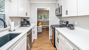 A compact kitchen with white cabinets, a microwave, toaster, and a coffee maker. - Walk to ND and Eddy Street, ProCleaned/Comfy/Updated (South Bend)