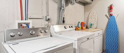 A laundry room with a Maytag washer and dryer, a fire extinguisher, and a surfboard.
