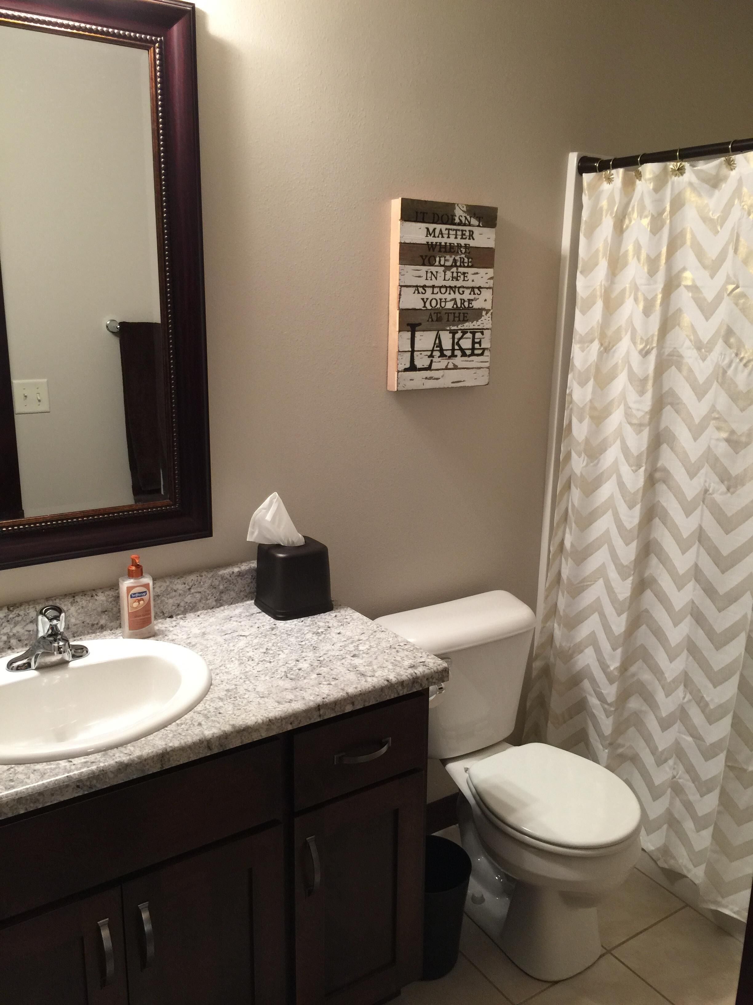 A bathroom with a sink, mirror, toilet, and a motivational quote on the wall.