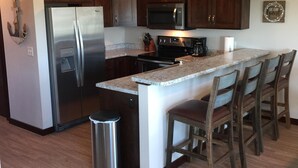 A modern kitchen with dark wood cabinets, stainless steel appliances, and a granite countertop.