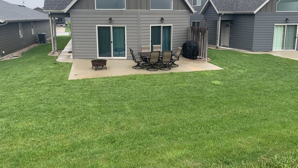 A modern house with a large patio, a dining table, and a grill.