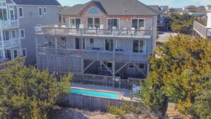 Ein zweistöckiges Haus mit Balkon, Swimmingpool und einem umzäunten Garten.