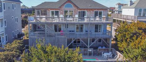 A two-story house with a balcony, a fenced deck, and a small outdoor seating area.
