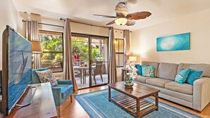 A living room with a sofa, coffee table, and a painting on the wall. - Where Serenity Awaits Kihei Spacious Condo Private Lanai Pool Near Beach (Kihei)