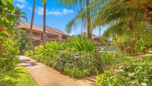 A pathway leading to a building surrounded by lush greenery and palm trees. - Where Serenity Awaits Kihei Spacious Condo Private Lanai Pool Near Beach (Kihei)
