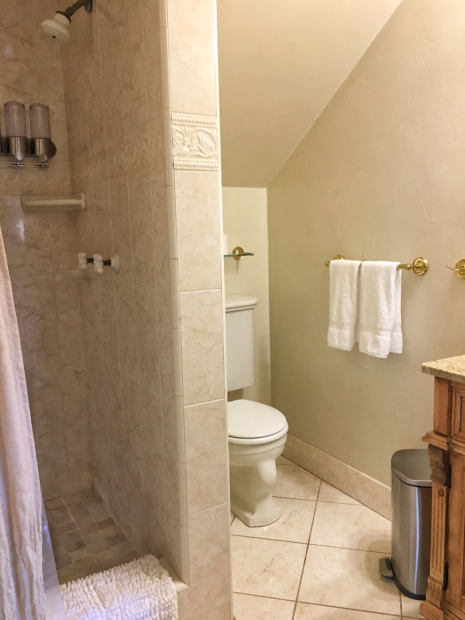 Un baño con ducha, inodoro y lavamanos con un perchero para toallas.