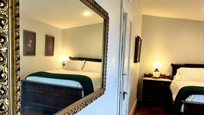 Een hotelkamer met twee bedden, een grote, versierde spiegel en een houten vloer.