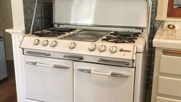 Een witte fornuis met vier branders, een afzuigkap en een dubbele oven.
