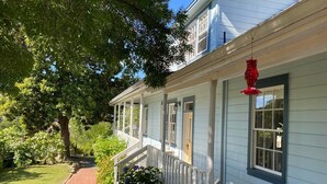 Een lichtblauwe woning met een overdekte veranda en een rode hanglamp.