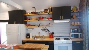 Cocina compacta con estufa a gas, refrigerador blanco y encimeras de madera.