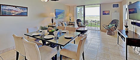 Amplia sala de estar con mesa de comedor, sillas, ventilador de techo y un televisor grande.