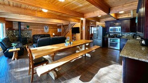 A wooden cabin interior with a dining area, kitchen, and seating space.
