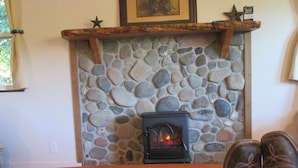 Lareira de pedra com fogão a lenha, um adorno em forma de estrela e um quadro emoldurado acima.