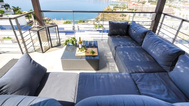 A balcony with a sofa, a small table, and a view of the sea and cityscape. - Magnificent Villa with private pool (Almuñécar)