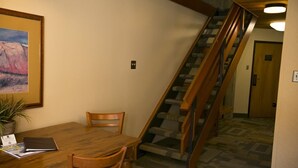 Ein Essbereich mit Holztisch und -stühlen, einer Treppe mit Holzwangen und einem Teppichboden.