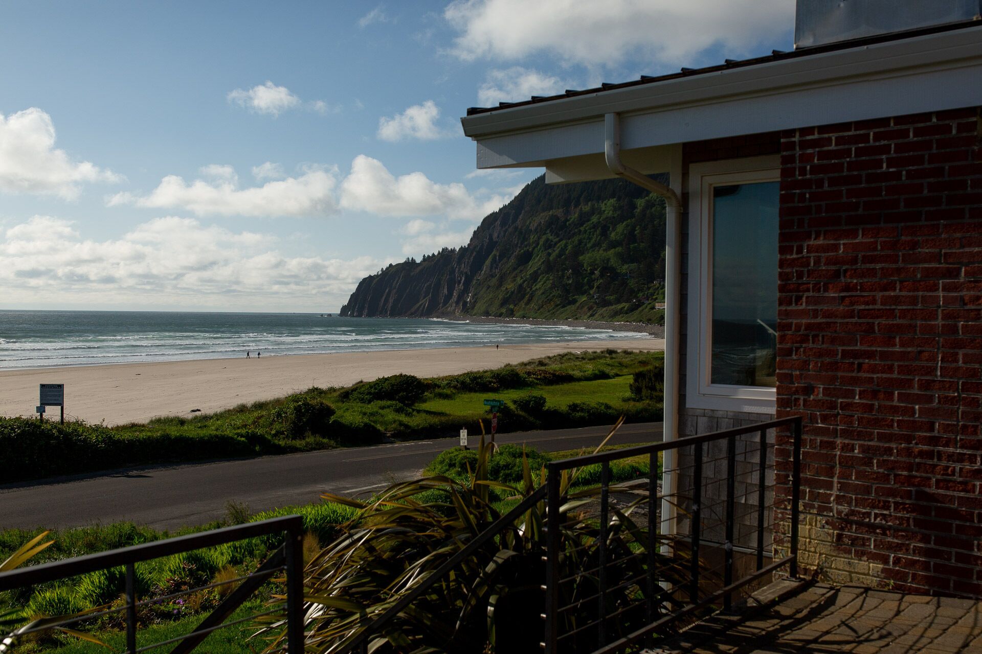 A coastal view from a building with a balcony overlooking a beach and cliffs.