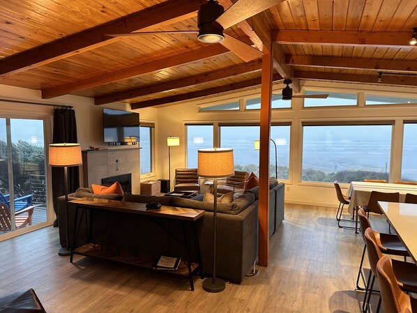 Un salón amplio con chimenea, ventanas grandes y un techo alto con vigas a la vista.