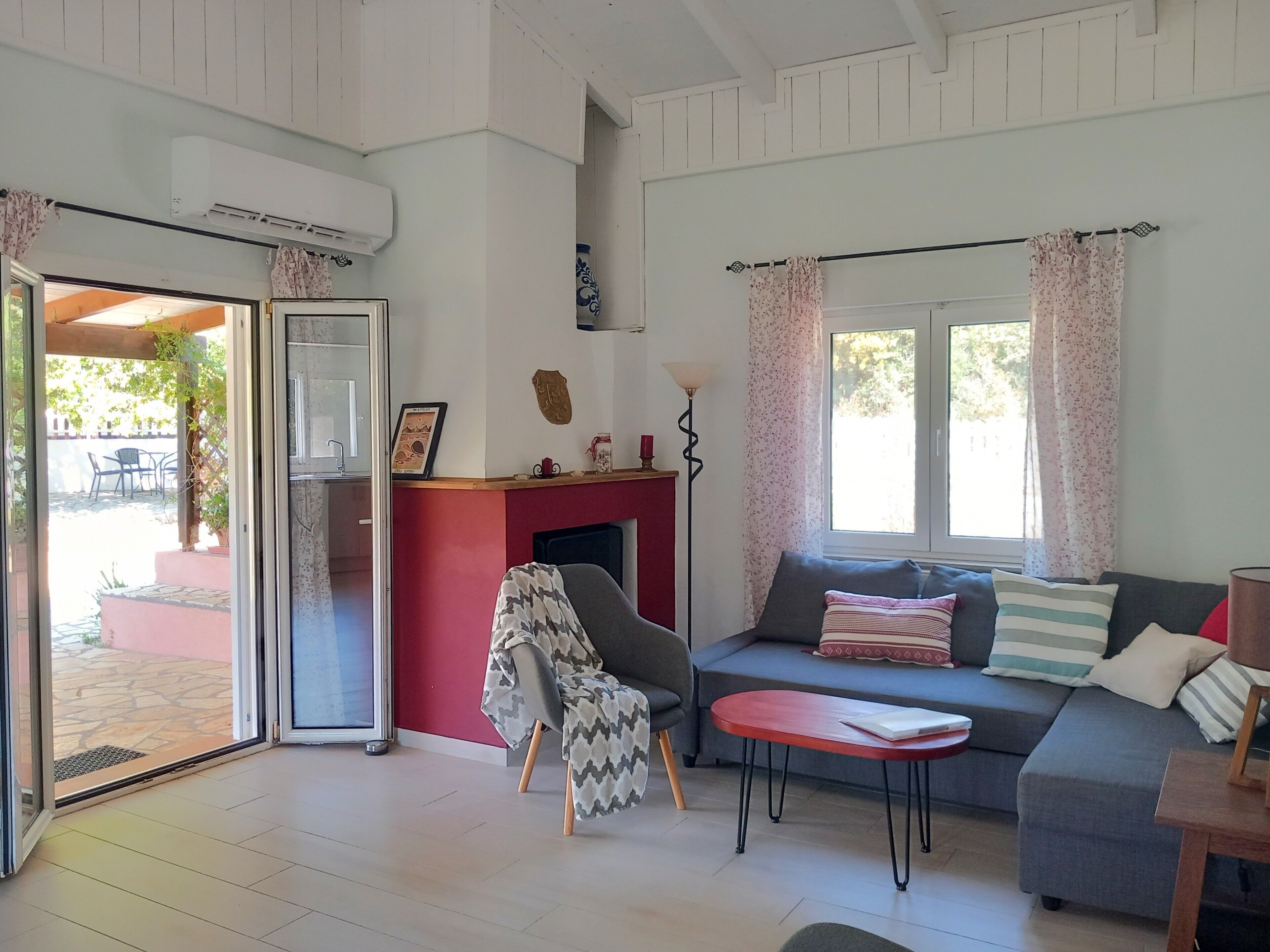 A living room with a sofa, a table, a fireplace, and a door leading to an outdoor area.