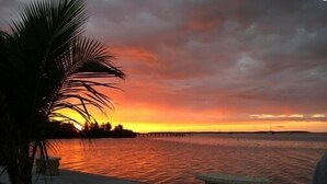 A sunset view over a calm body of water with a pier extending into the distance. - Bayside: Bayfront villa W/ free onsite boat ramp marina & trailer parking. (Islamorada)