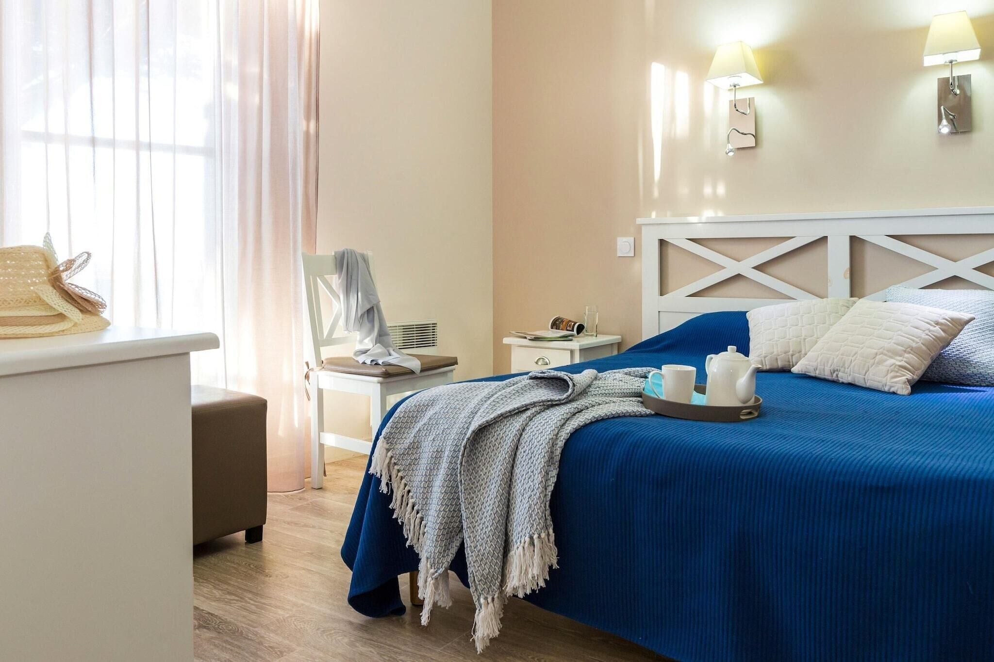 A hotel room with a bed, bedside table, lamp, and a chair.