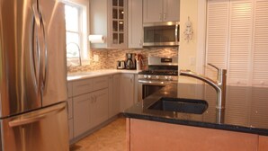 A modern kitchen with stainless steel appliances, a black countertop, and a built-in oven. - Afton Station Cottage -Beautifully Renovated Blue Ridge Scenic Historic Setting (Afton)